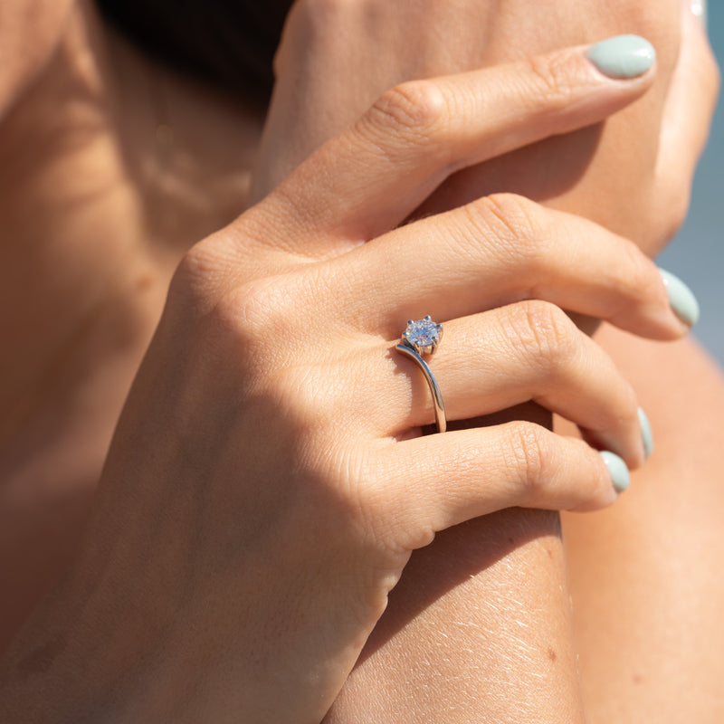 Model wears The Akilina ring close-up highlighting offset centre diamond and feminine curved silhouette