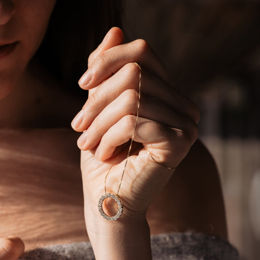Diamond Circle Necklace in yellow gold draped over hand