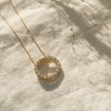 Diamond Circle Necklace in yellow gold flat laid on linen cloth