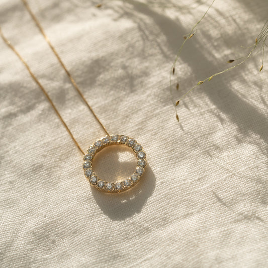 Diamond Circle Necklace in yellow gold flat laid on linen cloth