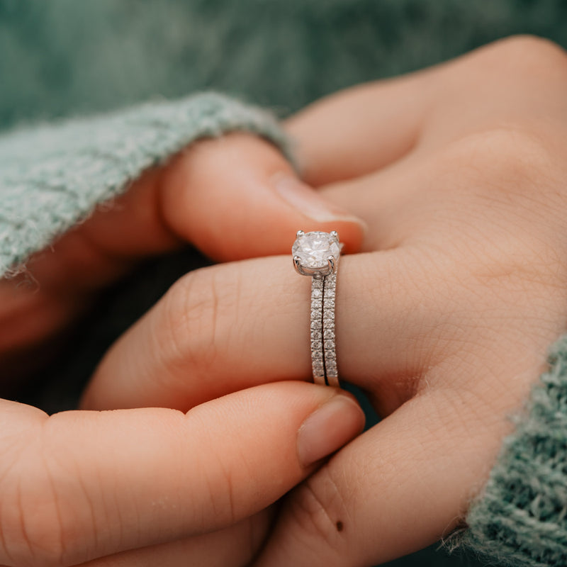 Model wearing platinum brial wedding set with ultra thin minimalist shoulder set diamond bands and green fluffy jumper