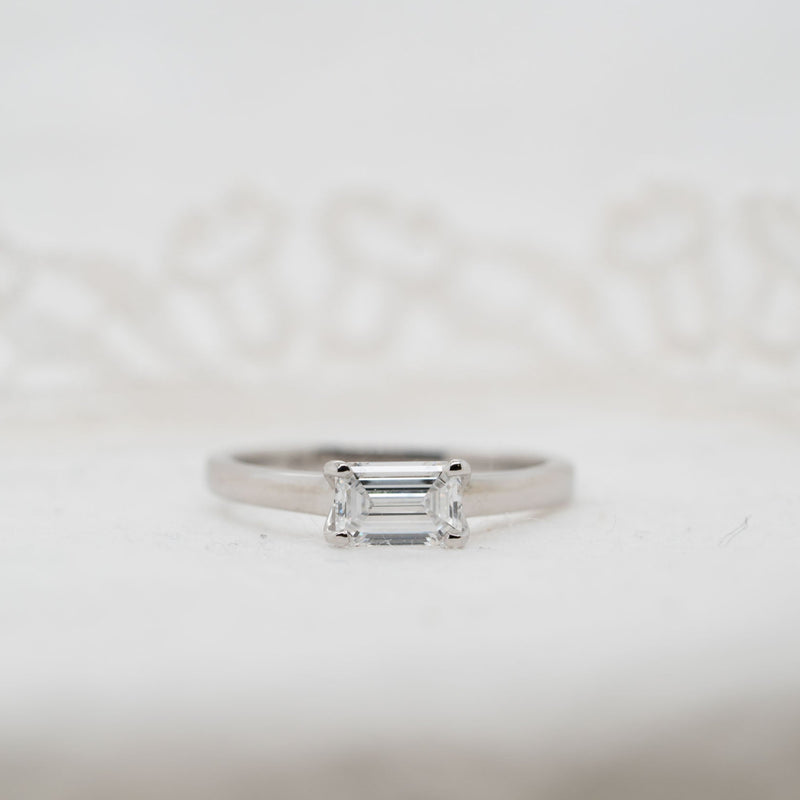 Silver ring with a rectangular lab grown gemstone diamond on a light gray background set east west
