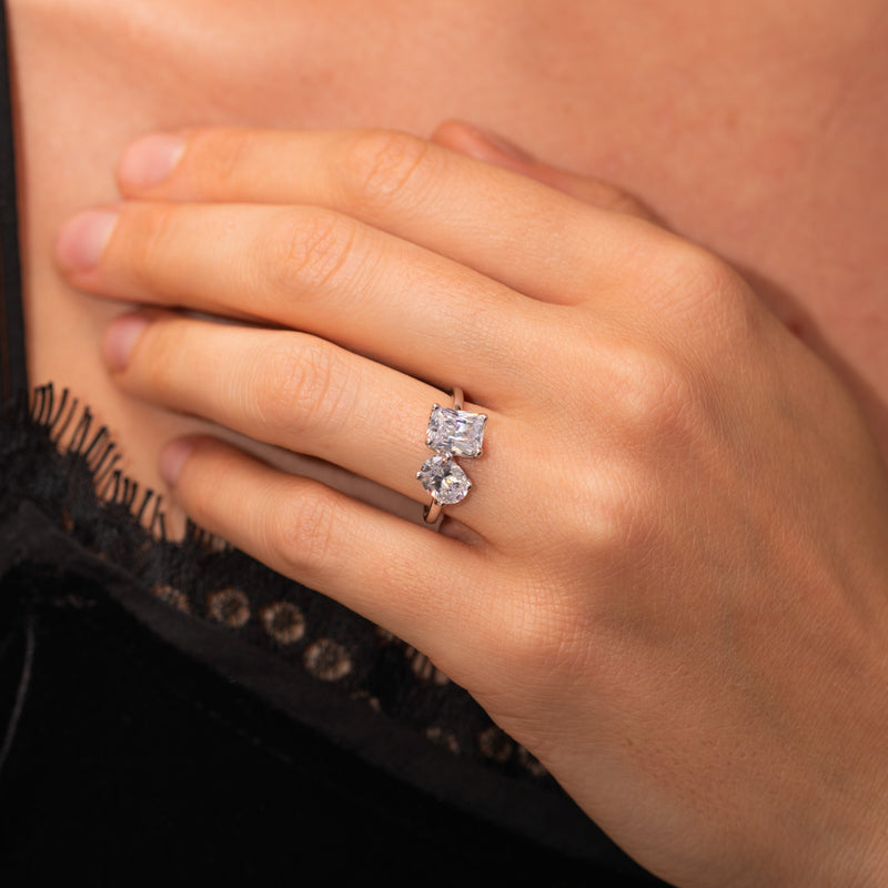 Close-up on hand: Oriana two stone toi et moi diamond engagement ring featuring lab grown oval and emerald diamonds. Ethica Diamonds