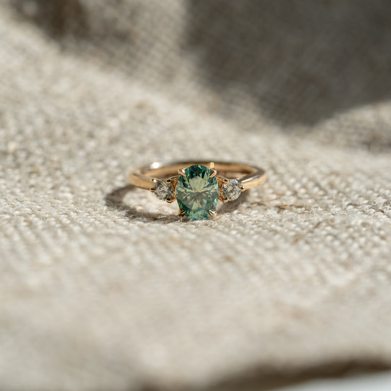 Seafoam green oval moissanite trilogy engagement ring by Ethica Diamonds with round lab diamond side stones