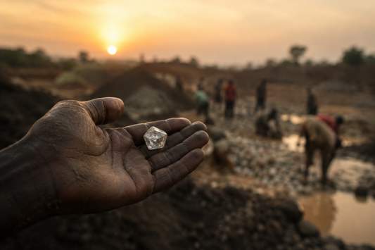Rough natural diamond held in a miner's hand at an artisanal diamond mine, highlighting the realities of diamond mining, conflict diamonds and ethical sourcing.