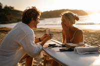 A couple sharing a romantic proposal moment on a golden sandy beach at sunset, waves gently lapping in the background