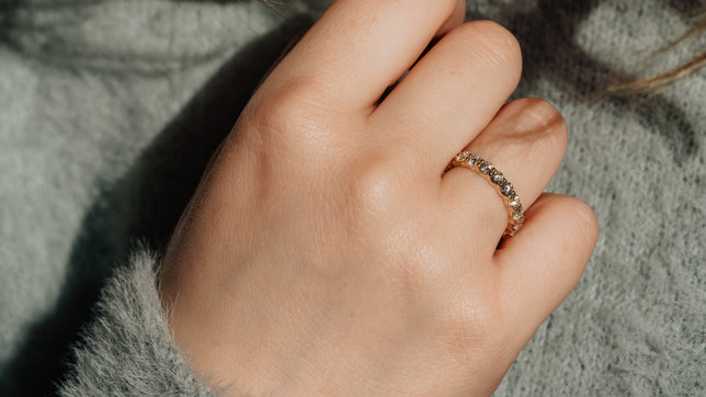 Close up of diamond set band worn on models hand. 