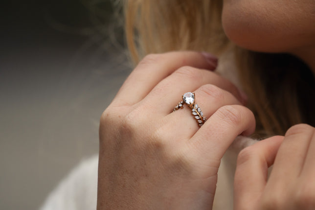 Close up shot of oval lab diamond halo engagement ring worn on hand. 