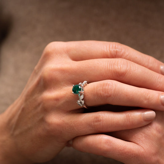 Close up of a hand wearing a ring with an emerald moissanite by Ethica Diamonds