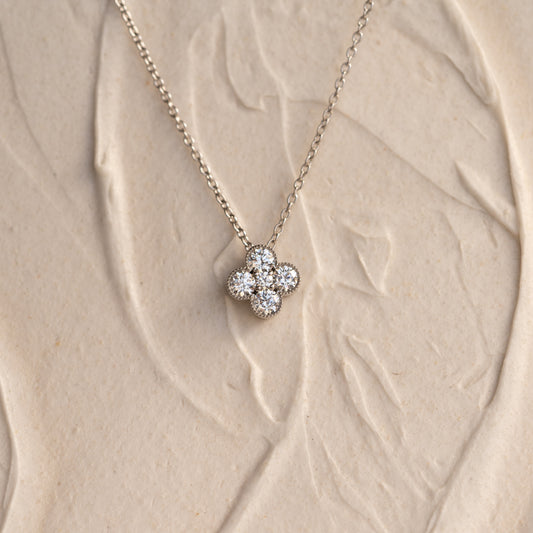 Gold necklace with a round brilliant diamonds on a beige textured background
