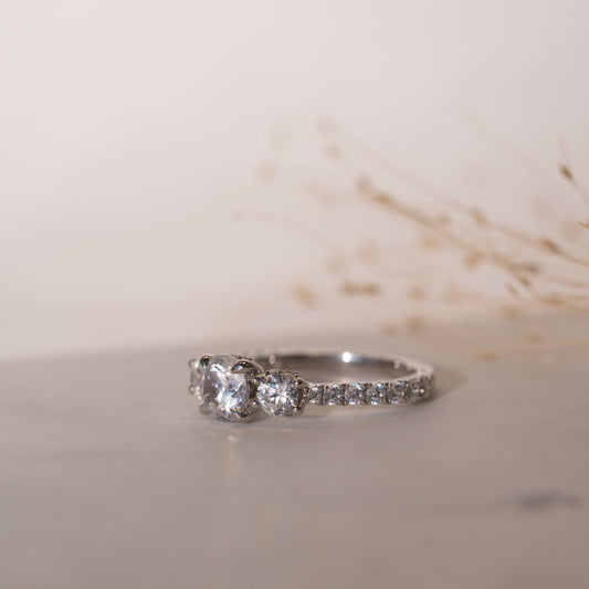 Graceful 3 stone engagement ring with diamond accented band and subtle halo detail