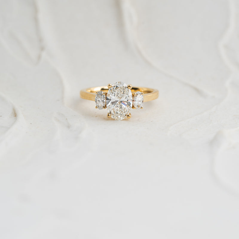 Large statement diamond engagement ring with 2 carat trilogy of oval cut lab grown diamonds and set in recycled 18k yellow gold