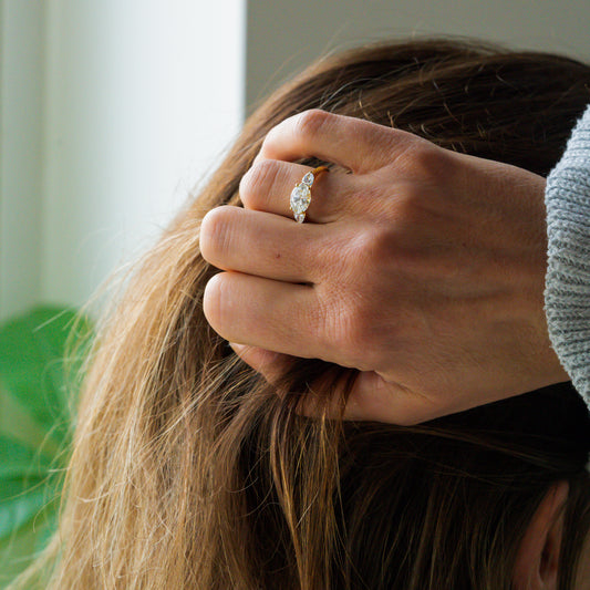 woman wears 3 stone oval engagement ring in east west setting with hand in hair