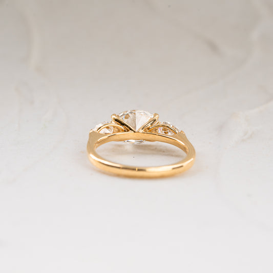 Flat lay of east west trilogy engagement ring shot from underneath. Recycled gold band and lab created diamonds