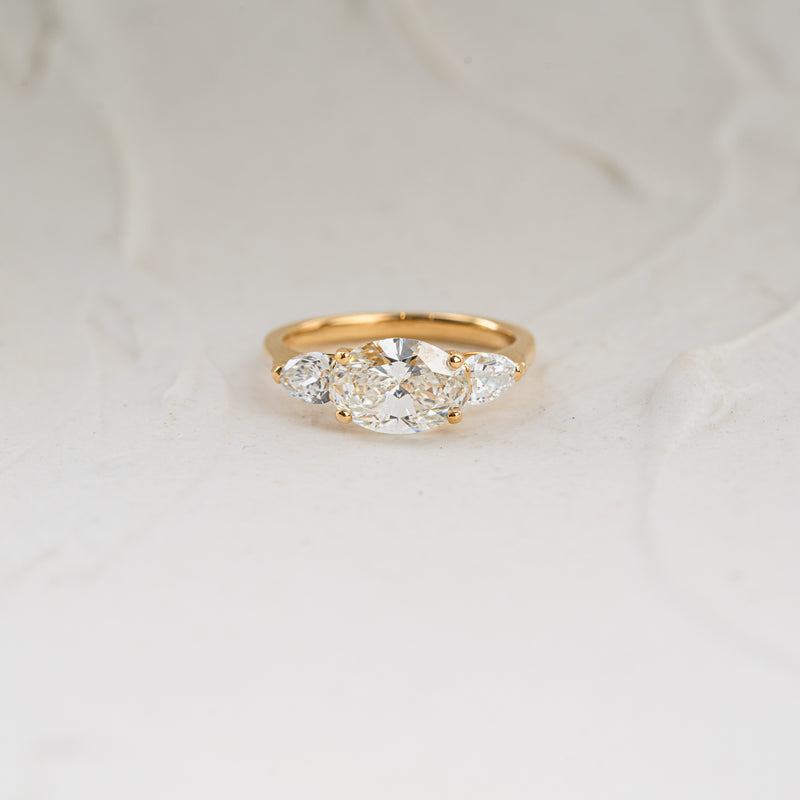 Claire Ring by Ethica Diamonds, east west oval center diamond with pear side stones in compass setting