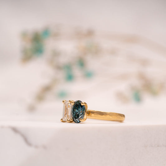 Custom bespoke two stone engagement ring with blue oval diamond and emerald cut diamond with hammered gold band