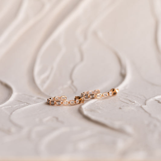 Profile view of Delia hoop with refined bezel-set diamond