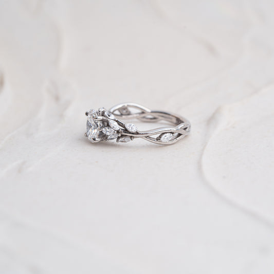 trellis flower bud diamond engagement ring laid flat on textured background
