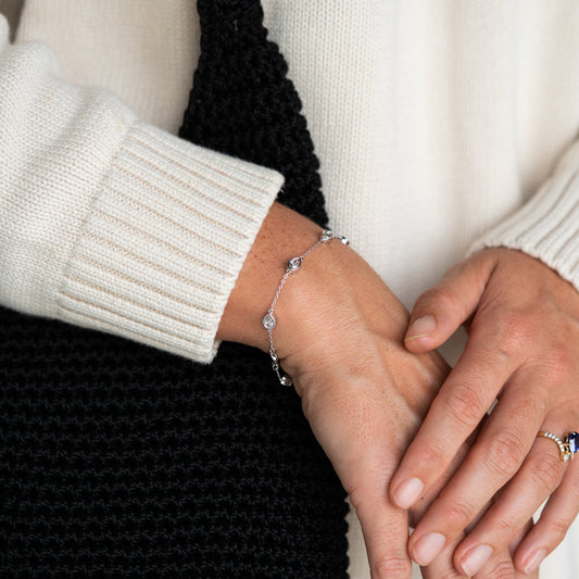 Close-up of a person's wrist wearing a white gold bracelet with a neutral background