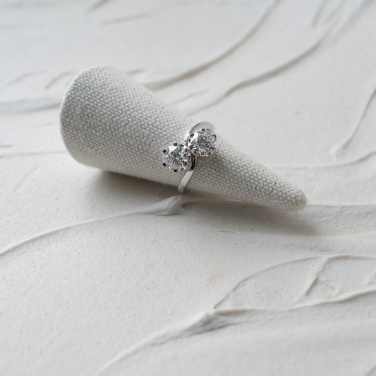 White gold ring with toi et moi diamonds on a white textured surface