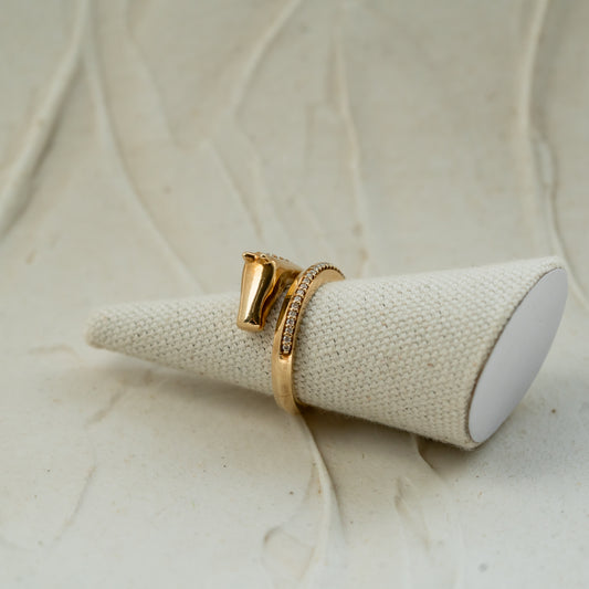 Gold horse head ring with lab diamond pave set into the tail against beige background