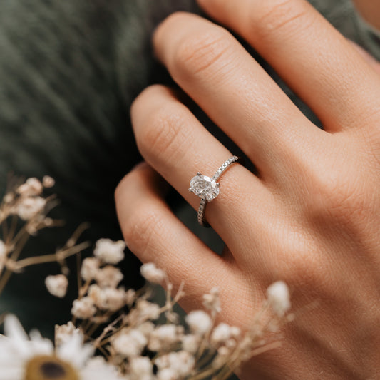 Model wears the aesa by ethica diamonds, a thin band oval diamond engagement ring with diamond set shoulders made in cornwall