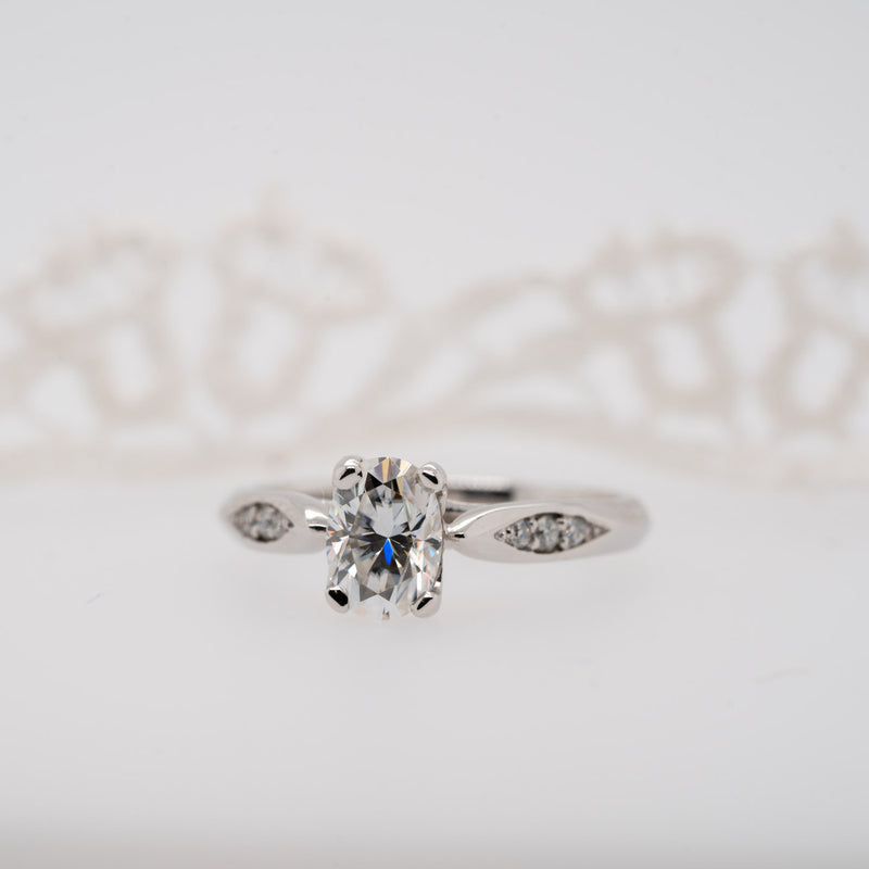 Oval diamond ring with knife edge shoulder set detail on white background