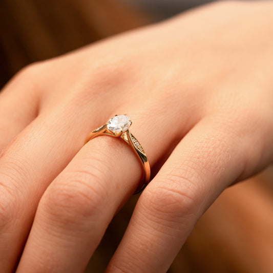 Side angle of celia knife edge solitaire engagement ring with open shoulders and gain set melee diamonds in shoulders