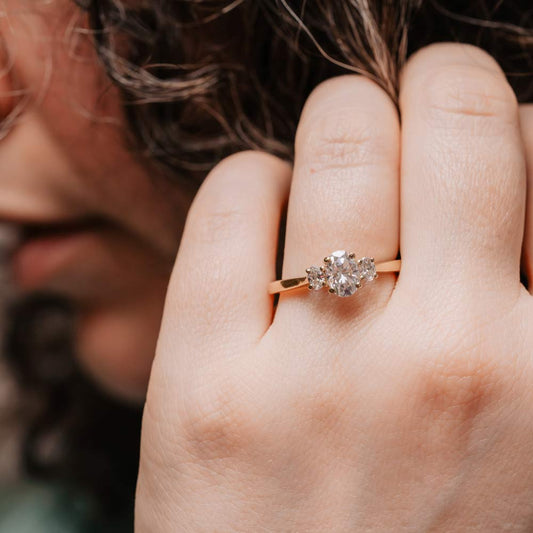 model wearing vintage inspired 3 stone trilogy diamond ring set in recycled rose gold