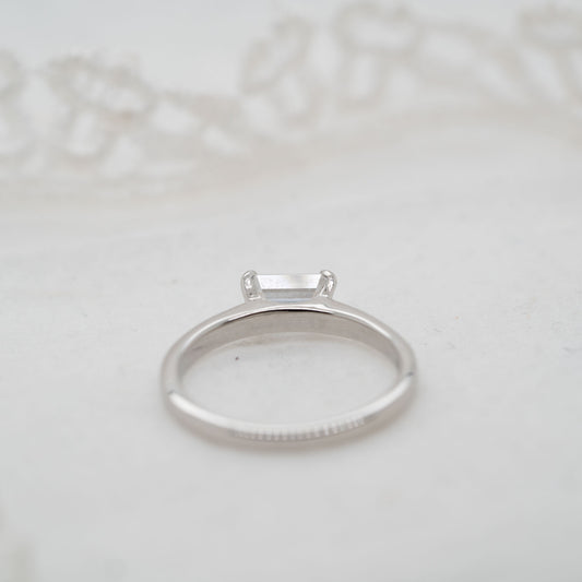 Platinum ring with a lab created man made diamond on a light gray background
