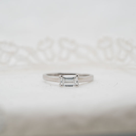 Silver ring with a rectangular lab grown gemstone diamond on a light gray background set east west