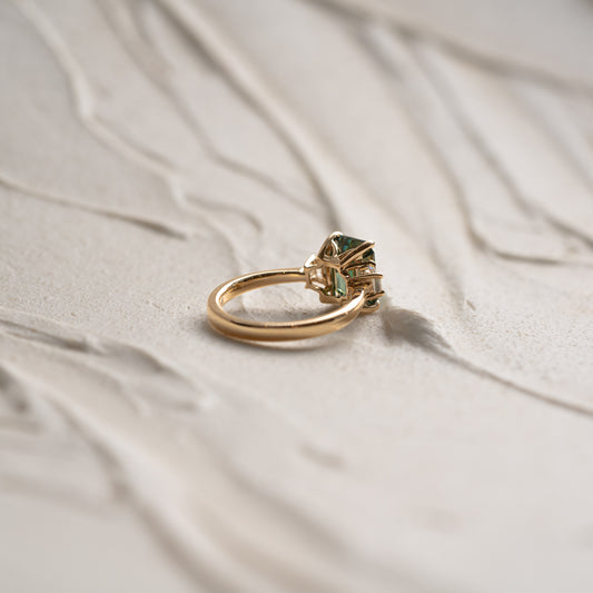 Yellow gold ring with a green gemstone on a beige fabric background