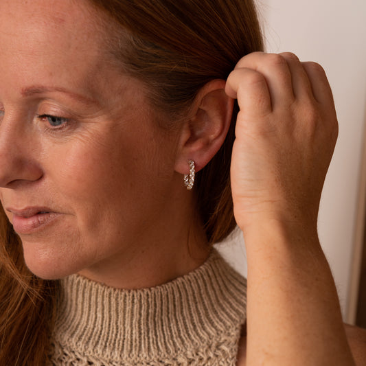 Detail view of 3.0mm round  lab diamonds in hoop earrings on a model