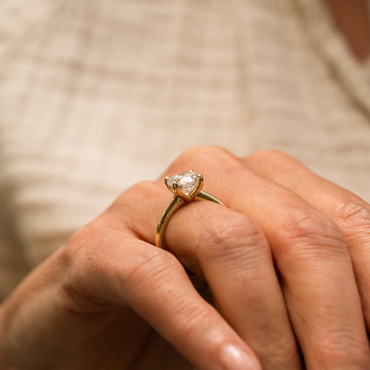 Model wears tulip style setting diamond ring with slim slender band and tall tapering shoulders