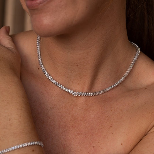 Close-up of a silver necklace from Cornwall on a person's neck with a neutral background