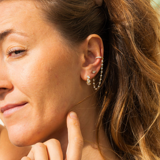 Close-up of a woman wearing earring hoop and chain in yellow gold 