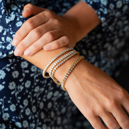 Close-up of a wrist wearing multiple bracelets with a floral-patterned fabric background