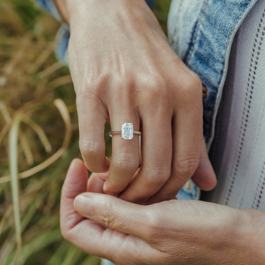 A close-up lifestyle shot of a person wearing a platinum ring with an old mine elongated cushion lab diamond on their finger
