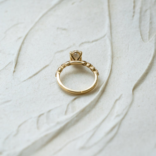 Gold ring with ethical lab diamonds on a textured beige surface. carbon negative jewellery made in cornwall
