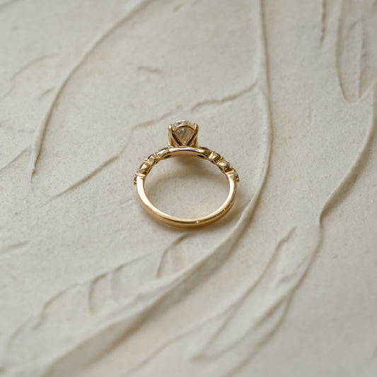 Gold ring with ethical lab diamonds on a textured beige surface. carbon negative jewellery made in cornwall
