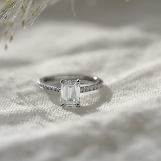 A recycled metal sustainable lab created diamond engagement ring with a clean row of diamonds on shoulders laid on cloth textured material