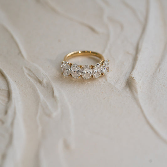 Gold ring diamond anniversary band with ethical lab diamonds on a textured beige surface
