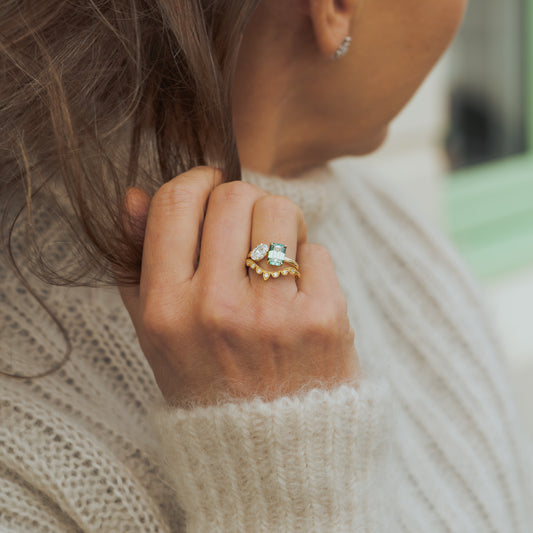 Model wearing delicate bridal set in recycled gold, two stone alternative engagement ring with green lab emerald diamond green