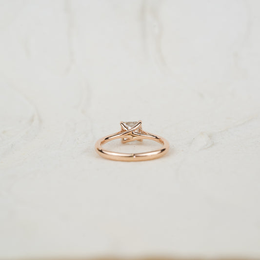 Rose gold ring with a diamond on a white neutral textured background