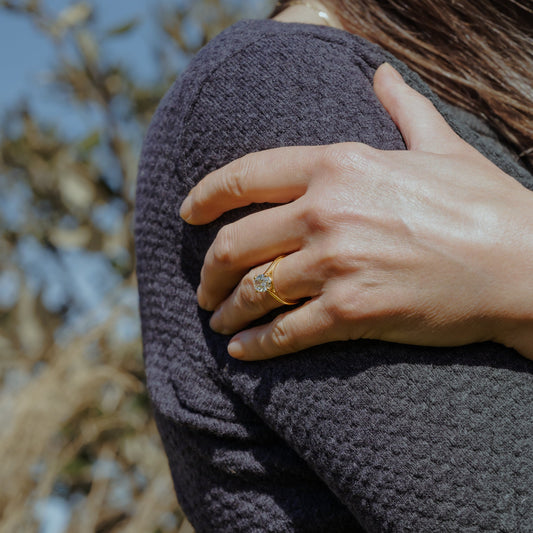 Woman wears dark grey jumper on spring sunny day with large 2 carat diamond engagement ring 