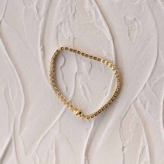 Ethically made Gold bracelet on a textured beige surface from Cornwall