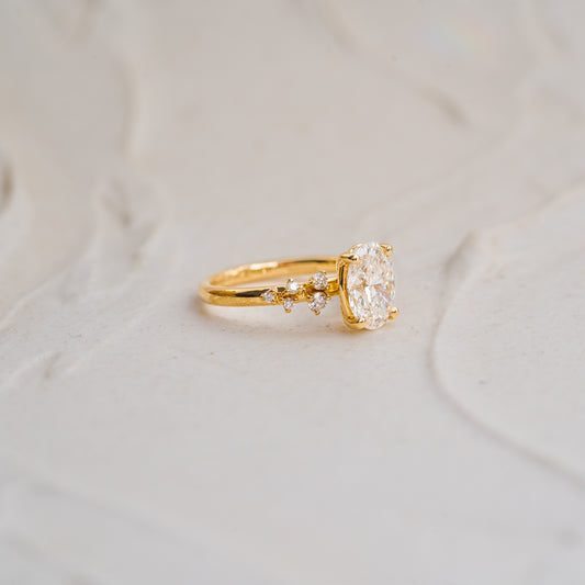 Detail shot of scattered lab grown diamond accents along the delicate band. 1ct yellow gold petite oval engagement ring