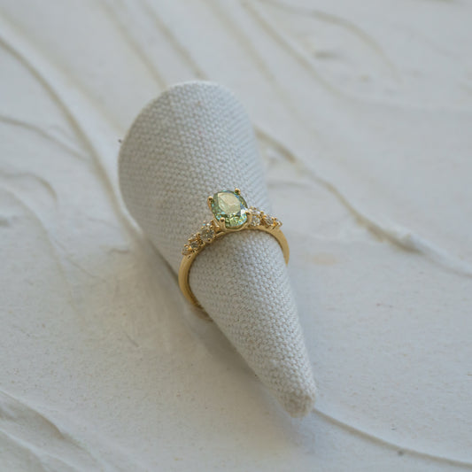 Beautiful aquamarine green diamond in yellow gold engagement setting on wavy background