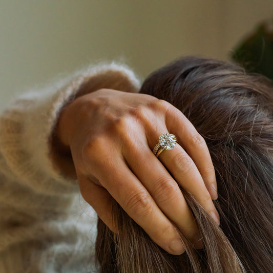 Hand wears 4ct carbon negative diamond ring holding hair, wearing a beige sweater.