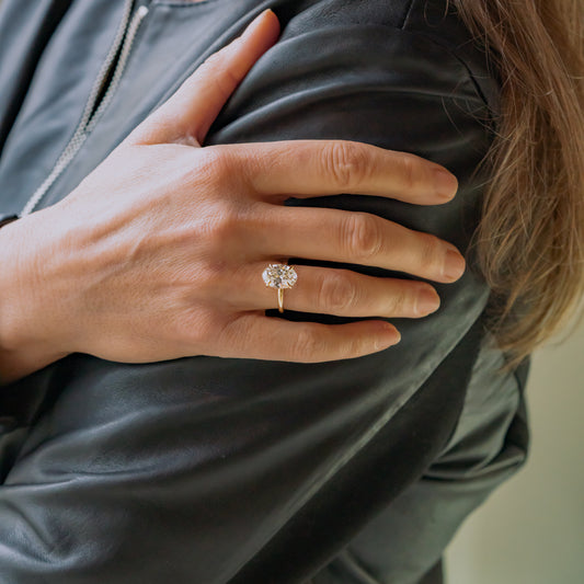 Model wearing 4ct oval cut diamond with hidden halo in 18k yellow gold against leather jacket 